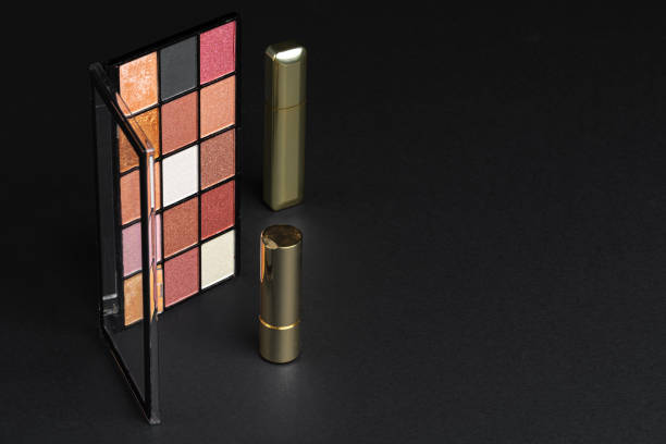 various makeup products on black texture background. close up